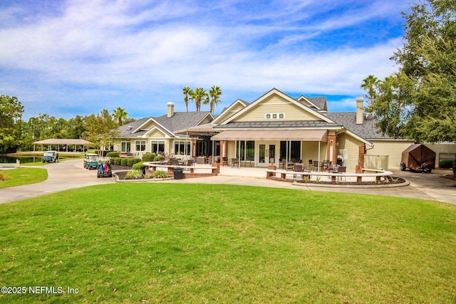 rear view of property with a patio, a yard, french doors, and concrete driveway