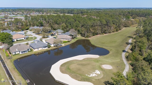 drone / aerial view featuring a water view, a wooded view, and golf course view