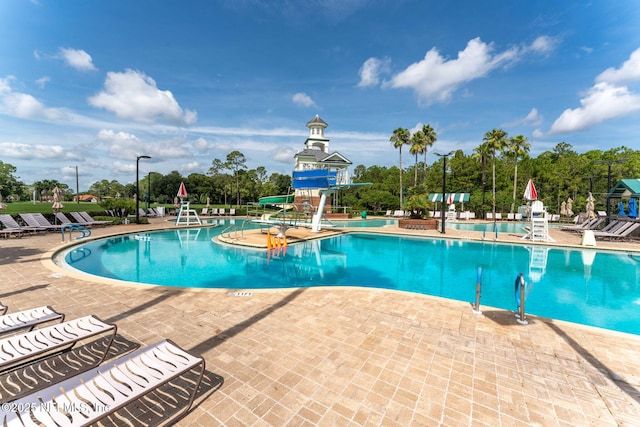 pool with a patio area and a water slide