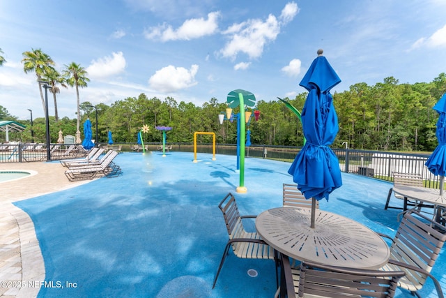 pool with playground community, a patio, a water play area, and fence