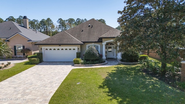 french country home featuring a front yard, roof with shingles, driveway, an attached garage, and stucco siding