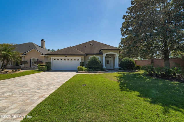 view of front of property with an attached garage, a front yard, stucco siding, a chimney, and driveway