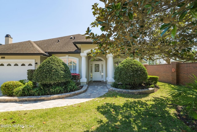 view of front of house featuring stucco siding, a front lawn, fence, an attached garage, and a shingled roof