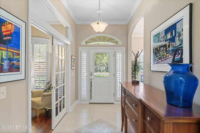 entrance foyer featuring a wealth of natural light, arched walkways, ornamental molding, and light tile patterned floors