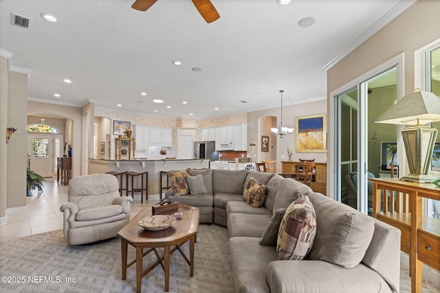 living area featuring light tile patterned floors, visible vents, recessed lighting, ornamental molding, and ceiling fan with notable chandelier