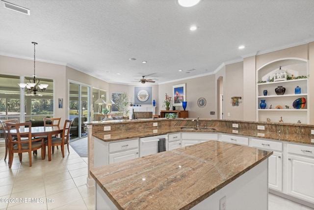 kitchen with visible vents, ceiling fan with notable chandelier, a textured ceiling, and ornamental molding