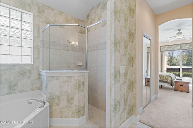 ensuite bathroom featuring a bath, a healthy amount of sunlight, a walk in shower, and ceiling fan