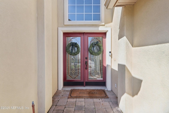 property entrance featuring stucco siding and french doors