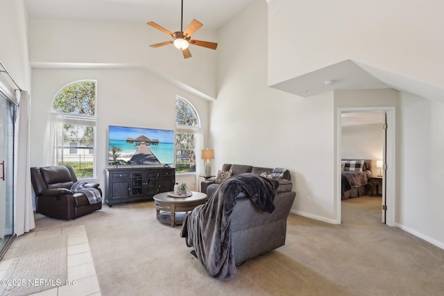 carpeted living room featuring a wealth of natural light, ceiling fan, and a towering ceiling