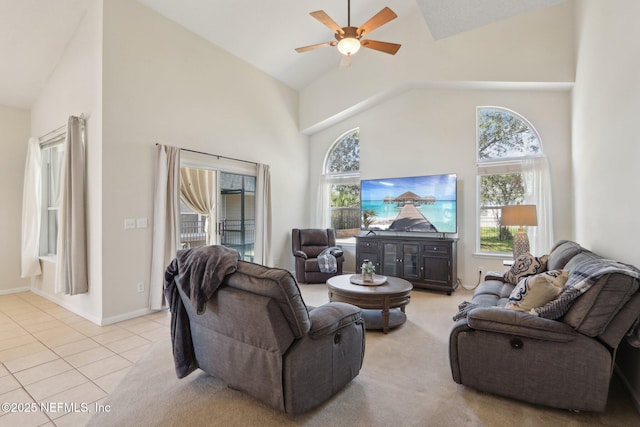 living area with ceiling fan, light tile patterned flooring, baseboards, and high vaulted ceiling