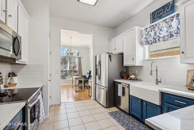 kitchen featuring light tile patterned floors, white cabinetry, stainless steel appliances, and blue cabinets