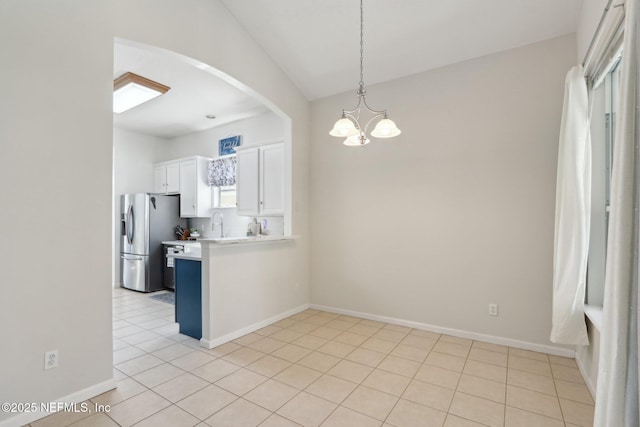 kitchen with a chandelier, decorative light fixtures, arched walkways, stainless steel fridge, and white cabinetry