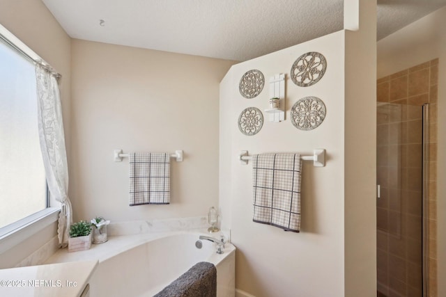 bathroom with a garden tub, a stall shower, and a textured ceiling