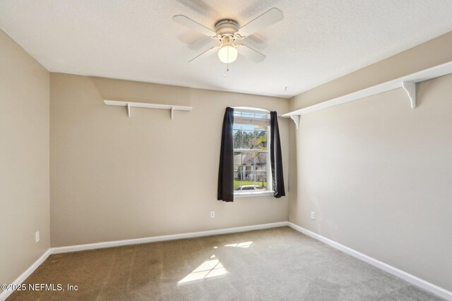 carpeted spare room featuring baseboards and ceiling fan