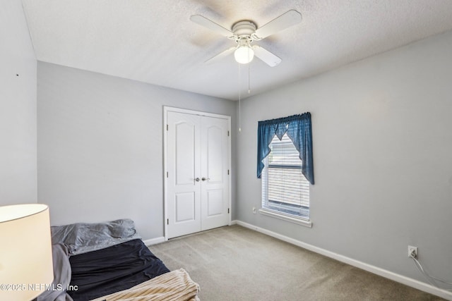 carpeted bedroom with a closet, a textured ceiling, baseboards, and a ceiling fan