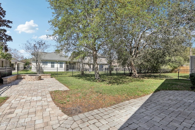 view of yard featuring a patio, a fire pit, and a fenced front yard