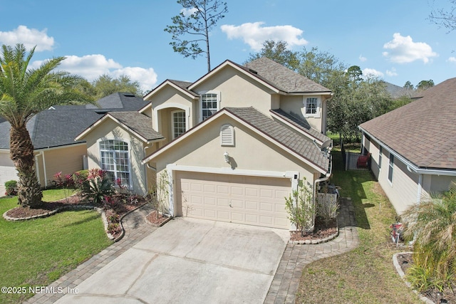 traditional-style home featuring roof with shingles, stucco siding, concrete driveway, a front lawn, and a garage