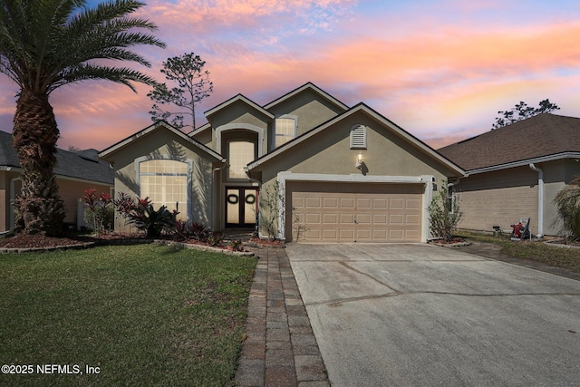 traditional home with an attached garage, a yard, driveway, and stucco siding