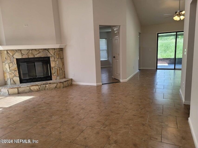 unfurnished living room with high vaulted ceiling, baseboards, a ceiling fan, and a fireplace