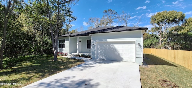 ranch-style home featuring an attached garage, concrete driveway, a front yard, and fence