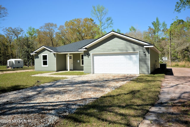 ranch-style home featuring a shingled roof, gravel driveway, a front lawn, cooling unit, and a garage