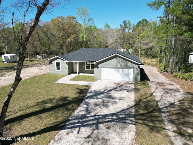 view of front of house with a view of trees, a front lawn, an attached garage, and driveway