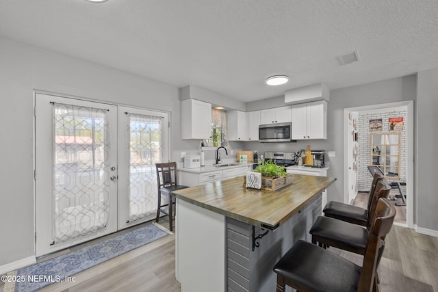 1516 Prospect St, Palatka, FL 32177 - kitchen featuring a breakfast bar, a sink, french doors, appliances with stainless steel finishes, and wooden counters