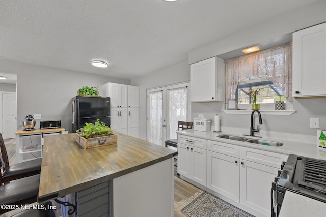 1516 Prospect St, Palatka, FL 32177 - kitchen with a breakfast bar, a sink, black appliances, wood counters, and white cabinetry