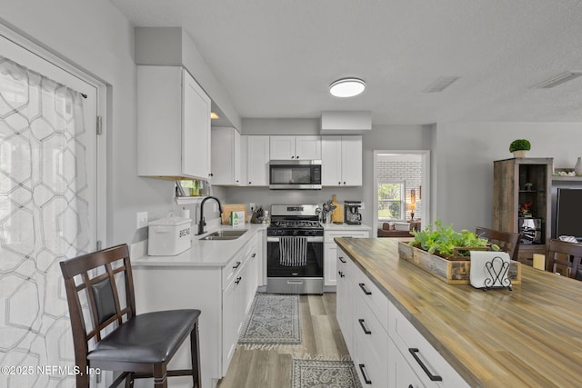 1516 Prospect St, Palatka, FL 32177 - kitchen with light wood-type flooring, a sink, wood counters, appliances with stainless steel finishes, and white cabinets