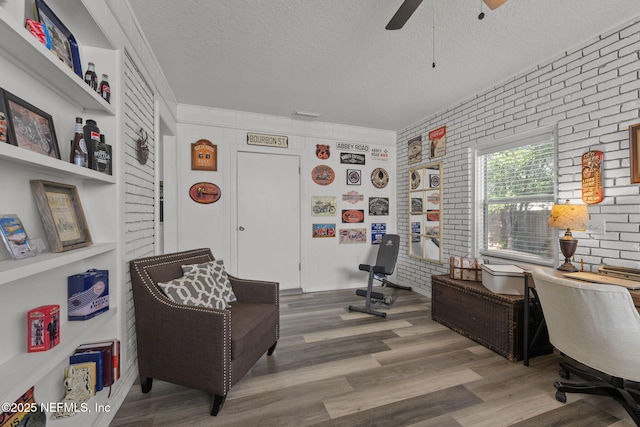 1516 Prospect St, Palatka, FL 32177 - living area with a ceiling fan, a textured ceiling, wood finished floors, and brick wall