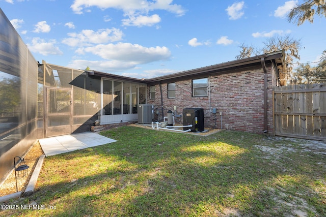 1516 Prospect St, Palatka, FL 32177 - rear view of property with central AC, fence, a yard, a sunroom, and brick siding