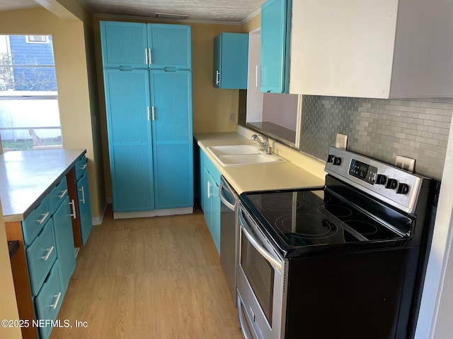 kitchen with a sink, blue cabinetry, light wood-style floors, appliances with stainless steel finishes, and light countertops