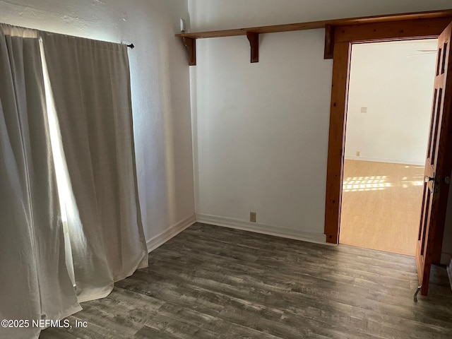 spare room featuring baseboards and wood finished floors