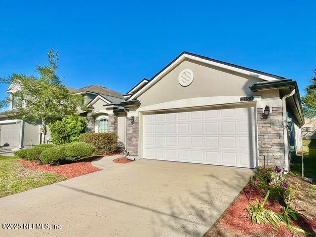 single story home with stone siding, stucco siding, driveway, and an attached garage