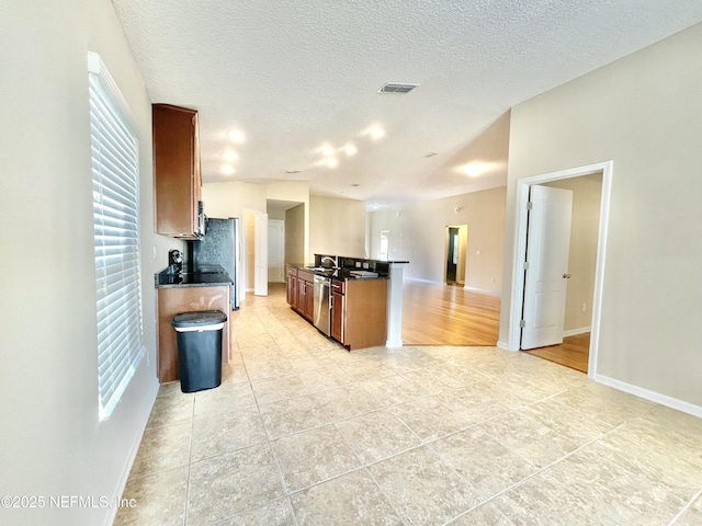 kitchen featuring visible vents, a sink, a textured ceiling, open floor plan, and light tile patterned floors