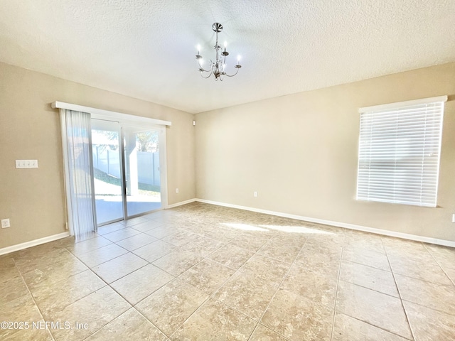 unfurnished room with a chandelier, light tile patterned floors, a textured ceiling, and baseboards