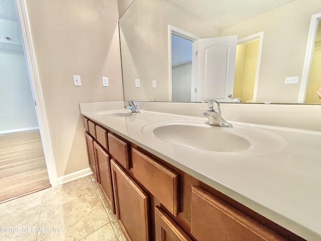 bathroom with a textured ceiling, tile patterned floors, double vanity, and a sink