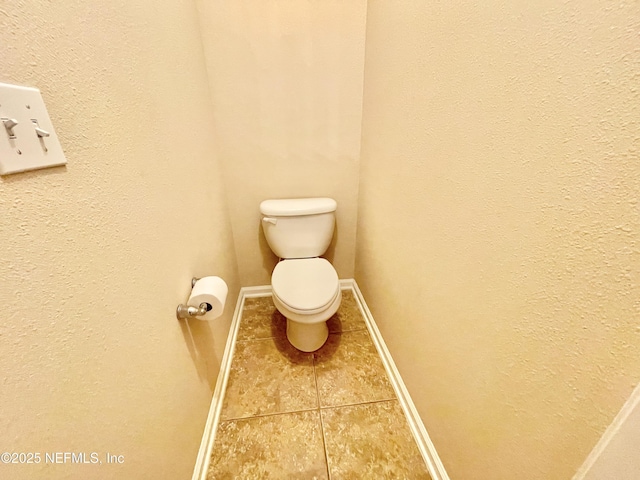 bathroom featuring tile patterned flooring, toilet, and baseboards