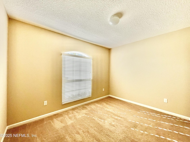 carpeted spare room with baseboards and a textured ceiling