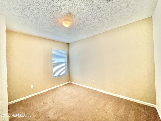 spare room with carpet flooring, a textured ceiling, and baseboards