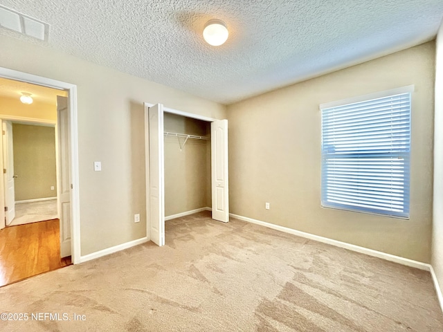 unfurnished bedroom featuring baseboards, visible vents, carpet floors, and a closet