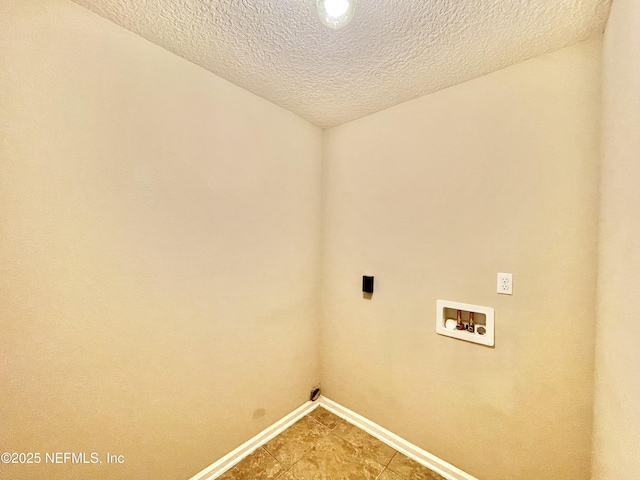 clothes washing area with baseboards, a textured ceiling, hookup for a washing machine, and laundry area