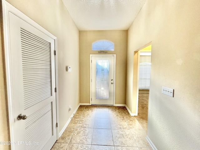 foyer with light tile patterned floors, baseboards, and a textured ceiling