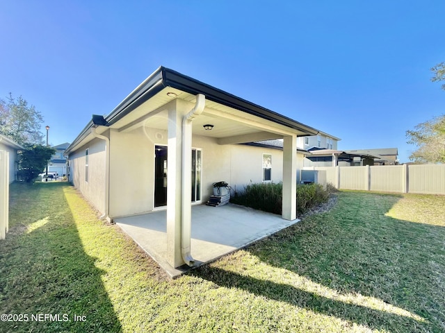 back of house with stucco siding, a patio, a lawn, and fence