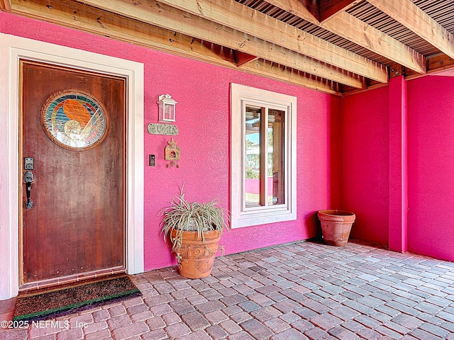 doorway to property featuring stucco siding and a patio