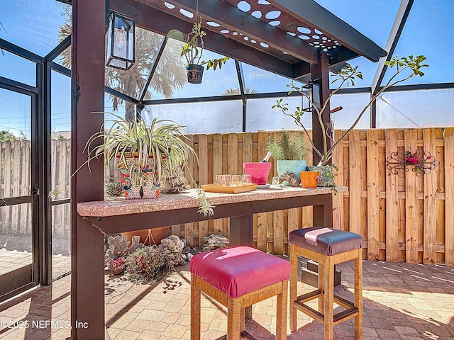 view of patio with a lanai, fence, and outdoor dry bar