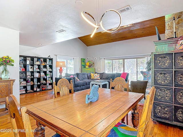 dining room featuring lofted ceiling, wood finished floors, visible vents, and wooden ceiling