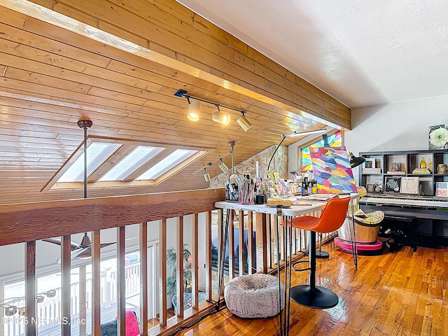 hall with hardwood / wood-style flooring, vaulted ceiling with skylight, and track lighting