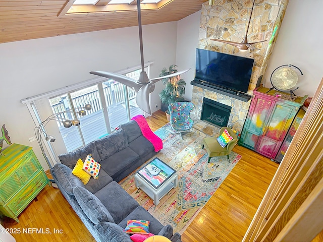 living area with high vaulted ceiling, wood finished floors, and a fireplace