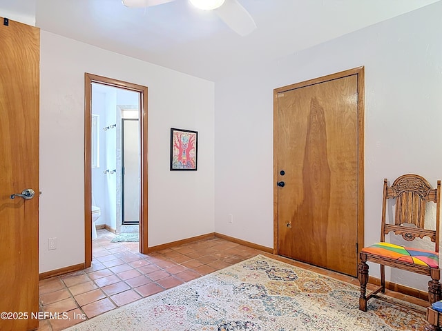 interior space featuring light tile patterned flooring, a ceiling fan, and baseboards